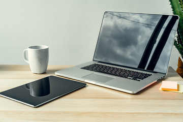 Laptop in a light room on working table with office supplies