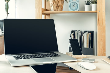 Laptop in a light room on working table with office supplies