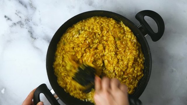 cooking pumpkin risotto in a non-stick pan. Italian Cuisine. marble kitchen