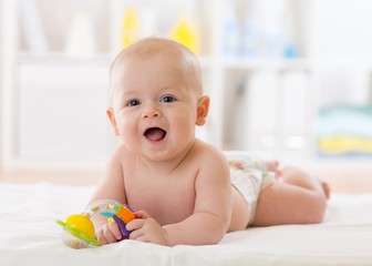 baby infant lying on belly weared diaper with teether toy in children room or nursery