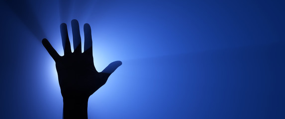 Silhouette of a raised hand. Spotlight in the background.