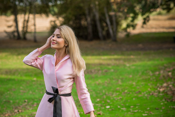 Fashionable concept. Romantic lady in pink trench outdoors 