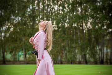 Fashionable concept. Romantic lady in pink trench outdoors 