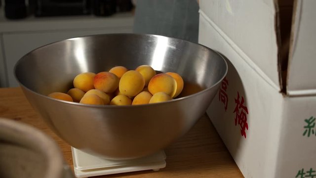 a Japanese female chef weighing Nanko-Ume plums at her home kitchen, Tokyo, Japan. July 2019. Camera fixed, close-up, high view
