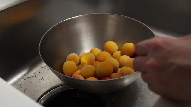 a Japanese female chef rinsing Nanko-Ume plums at her home kitchen, Tokyo, Japan. July 2019. Camera fixed, close-up, high view