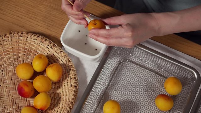 a Japanese female chef removing the stem of Nanko-Ume plums at her home kitchen, Tokyo, Japan. July 2019. Camera fixed, close-up, bird's eye view