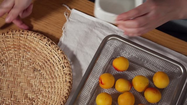 a Japanese female chef removing the stem of Nanko-Ume plums at her home kitchen, Tokyo, Japan. July 2019. Camera fixed, close-up, bird's eye view