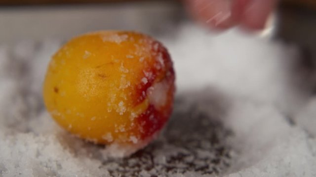 a Japanese female chef salting Nanko-Ume plums at her home kitchen, Tokyo, Japan. July 2019. Camera fixed, extreme close-up, neutral view