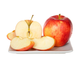 One whole gala apple with one sliced on a small rectangular plate isolated on white. Gala is a clonally propagated apple cultivar with a mild and sweet flavor.