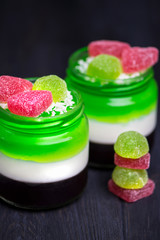 homemade multicolored jelly of fruit juices and milk in a glass jar on a dark background
