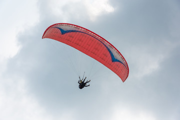 2 people flying in the sky with red paragliders