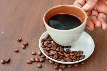 Close up at Old man hand hold a handle of coffee cup for drinking in the morning.Elderly lifestyle.People famous intake black coffee in the morning for freshness.Flat lay.