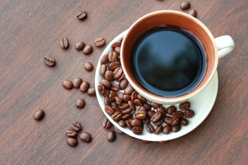 Top view and closeup,a cup of black coffee with  roasted Robusta beans on wooden background.Copy space for insert text.Can use for banner.