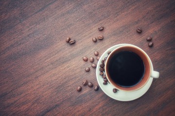 Top view,a cup of black coffee with  roasted Robusta beans on wooden background.Copy space for insert text.Can use for banner.Vintage technique.