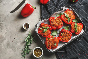 Baking dish with tasty stuffed pepper and sauce on grey background
