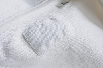 Blank white clothes label on new cotton shirt background