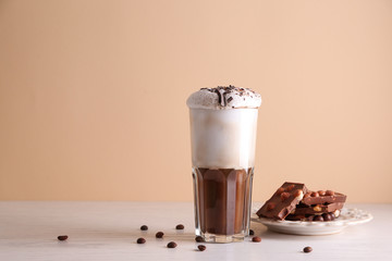 Glass of tasty frappe coffee and sweets on table