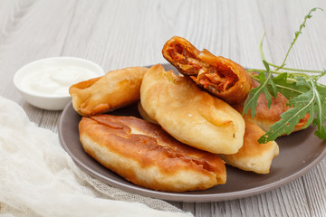 Plate with fried pies on wooden boards.