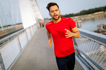 Fototapeta premium Handsome young man running across the bridge.