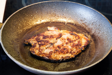 frying beef steak in pan on ceramic electric range