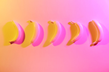 Ripe painted bananas on color background