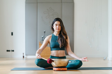 Sportliche junge Frau beim Yoga mit einer Klangschale