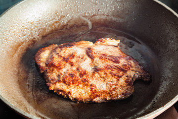 roasting beef steak in frying pan on range