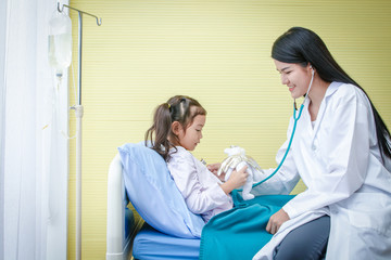 Obraz na płótnie Canvas Asian female doctors use stethoscope to check the heartbeat A little girl in a hospital bed. Concept of child care.