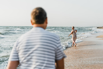 Romantic adult couple standing together on the beach. Mature pair relax at the seaside on holiday. Happy familiy walking and holding hands near sea. Husband embracing wife. Love story near the sea