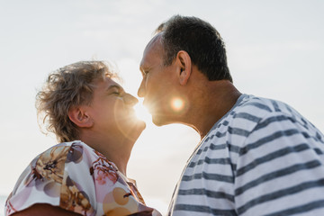 Romantic adult couple standing together on the beach. Mature pair relax at the seaside on holiday. Happy familiy walking and holding hands near sea. Husband embracing wife. Love story near the sea