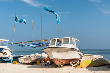 Fototapeta na wymiar Colorful boats lying on the beach of sunny tropical island, against a bright blue sky and turquoise water, Maafushi Island, Maldives, Indian Ocean. Amazing tropical holidays.