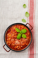 Traditional italian Bolognese sauce in saucepot an old dark wooden background. Top view, copy space