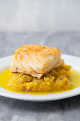 cod fish with mashed potato and olive oil on white dish
