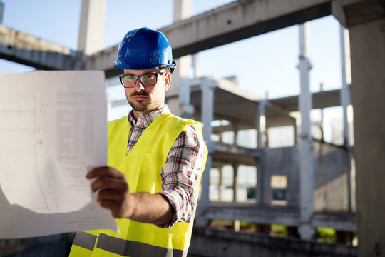 Engineer working on construction site and holding blueprint