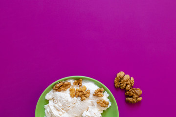 Vanilla ice cream with walnut on green plate.