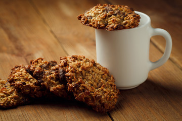 Cup with hot coffee milk and homemade backing chocolate cookies on a wooden table