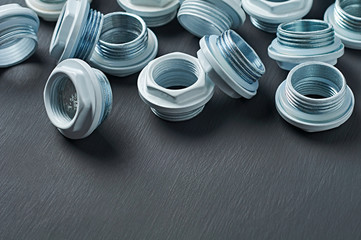 Scattered many new white nuts with double thread for bimetallic or aluminum radiator for heat room lies on dark concrete table in workshop. Space for text