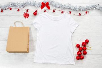 Close up white blank template t shirt with copy space paper bag. Christmas Holiday concept. Top...