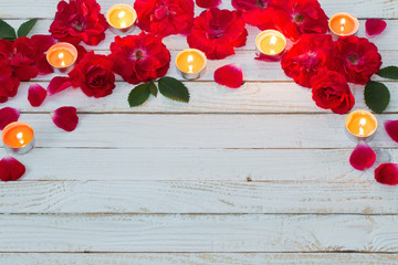 red roses and burning candles on wooden white background