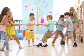 group of preschool children play and pull rope together in competition