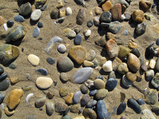 Wet sea pebbles on the sand