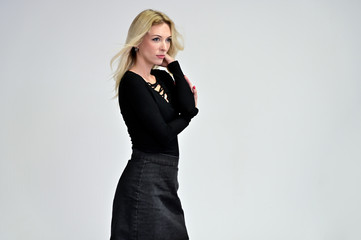Studio portrait of a pretty blonde student girl with long hair in a black blouse on a white background. Smiling at camera with emotions in various poses.
