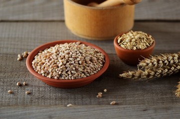 Wheat grain in dishes on the table.grains and wheat ears on a wooden table, top view