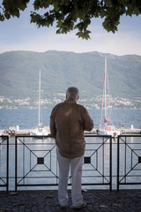 Un homme regardant un port. Un retraité regardant des bateaux sur le Lac Majeur. Un retraité en...