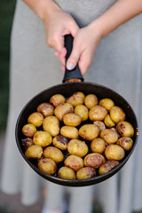 girl holds pan with whole baked potatoes.