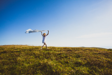 Fototapeta premium Woman run with white textile high up in the mountains