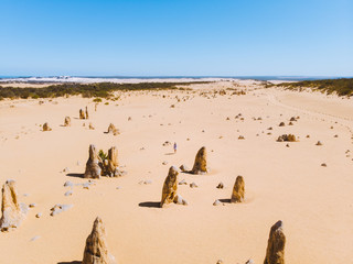 Fototapeta na wymiar Aerial drone perspective of a lone girl walking through the iconic Pinacles of Western Australia. 