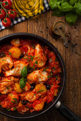 Traditionally prepared cod in Spanish. Served in tomato sauce with boiled potatoes, olivki and basil. Top view.