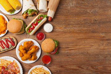 Fototapeta na wymiar Mix of fast food, street dishes. Background with copy space. Top view. Natural wooden background.