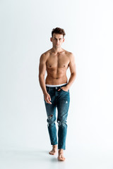 Fototapeta premium handsome man in jeans walking with hand in pocket on white